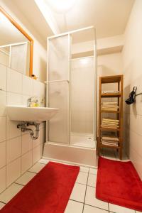 y baño con ducha, lavabo y alfombra roja. en Ferienwohnung Mittendrin, en Bergisch Gladbach