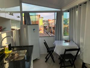 cocina con mesa, sillas y ventana en Kitnet Central, en Arraial do Cabo