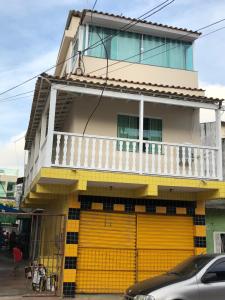 a building with a yellow door and a balcony at Kitnet Central in Arraial do Cabo