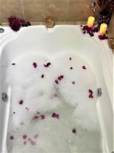 una bañera con flores púrpuras. en Suítes Bouganville en Porto de Galinhas