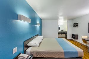 - un grand lit dans une chambre dotée d'un mur bleu dans l'établissement Studio 6 Fort Worth, TX - Stockyards East, à Fort Worth