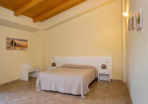 1 dormitorio con 1 cama blanca y 2 mesas en Il Biscardino, en Cropalati