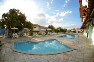 a pool at a resort with chairs and umbrellas at Caruaru Park Hotel in Caruaru