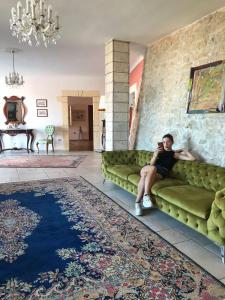a man sitting on a green couch in a living room at Hotel Boutique Il Castellino Relais in Vieste
