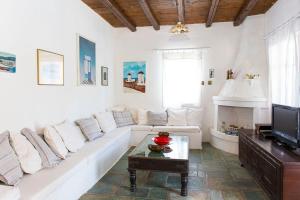 a living room with a white couch and a tv at Traditional Mykonian Villa in Ornos