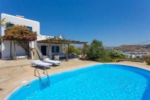 a large blue swimming pool in front of a house at Traditional Mykonian Villa in Ornos