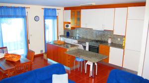 a kitchen with white cabinets and a table and chairs at Nibho Apartment in Esposende