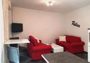 een woonkamer met 2 rode stoelen en een tafel bij EXCELSIOR Apartments Rovinj in Rovinj