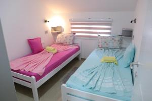 two beds in a room with pink and blue at Apartmani "ROSHU" in Soko Banja