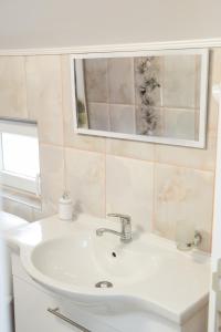 a bathroom with a white sink and a mirror at Apartmani "ROSHU" in Soko Banja