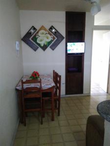 uma sala de jantar com uma mesa e cadeiras e uma televisão em Kitnet em Guarapari em Guarapari