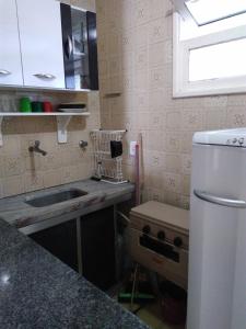 a small kitchen with a sink and a refrigerator at Kitnet em Guarapari in Guarapari