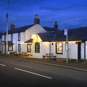 een wit gebouw aan de straatkant bij The Farmers Inn in Dumfries