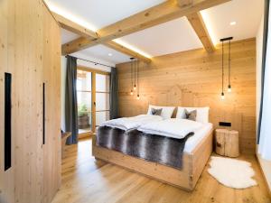 1 dormitorio con 1 cama grande y paredes de madera en Chalet Novalis, en San Candido