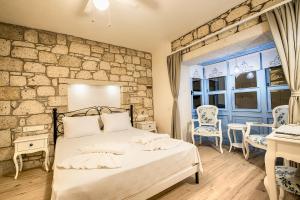 a bedroom with a bed and a stone wall at Bademli Konak Otel in Datca