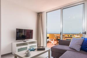 a living room with a couch and a tv at Ocean View Penthouse II in Gran Tarajal