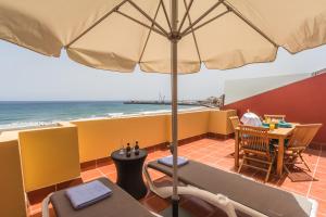 a patio with a table and an umbrella and the ocean at Ocean View Penthouse II in Gran Tarajal