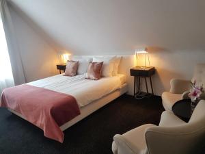 a bedroom with a bed with two lamps and two chairs at Hotel Herrloh in Winterberg