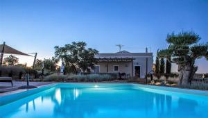 a large blue swimming pool in front of a house at Espargosa Monte de Baixo & Art in Castro Marim