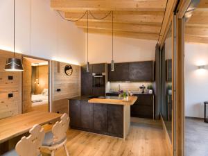 a kitchen with wooden cabinets and a wooden table and chairs at Chalet Novalis in San Candido