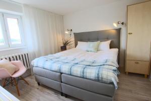 a bedroom with a large bed and a chair at Apartament Stary Port 1 in Bydgoszcz