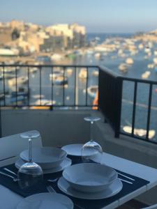 a table with plates and wine glasses on a balcony at Sunrise Creek in Marsaskala