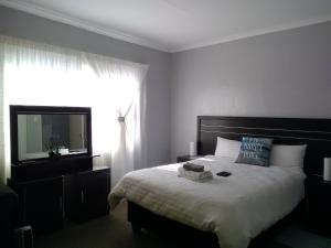 a bedroom with a large bed and a television at Noble Hearts Bed & Breakfast in Maseru