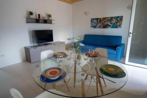 a living room with a glass table and a blue couch at Val Mora Bio Apartments in Garda