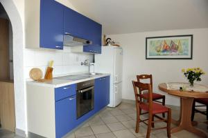 a kitchen with blue cabinets and a table with a chair at Apartman Branka in Kornić