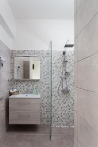 uma casa de banho com um chuveiro, um lavatório e um espelho. em Seaside Studios em Áyioi Apóstoloi