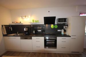 a kitchen with white cabinets and a black counter top at Ferienwohnung Loreley in Lierschied