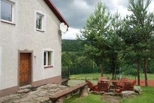 a patio with chairs and a table next to a house at Apartamenty pod Werchowyną in Chyrowa