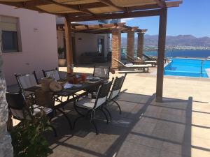 a patio with a table and chairs and a pool at Endless View Villa in Agios Nikolaos