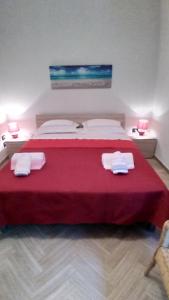 - une chambre dotée d'un grand lit avec des draps rouges et des serviettes blanches dans l'établissement "Emozioni Salentine", à Torre dell'Orso
