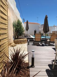 a patio with umbrellas and chairs and a pool at Casa Malpique in Albufeira