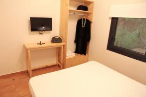 una piccola camera con letto e televisore di Eva 's Paradise a Pefkari
