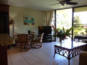 sala de estar con mesa, sillas y TV en Aloha KAI - Resort Condo, en Kihei