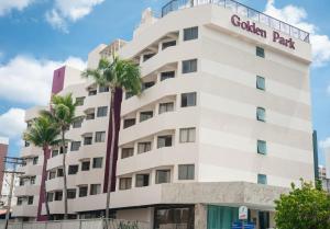 um edifício branco com uma palmeira em frente em Hotel Golden Park Salvador em Salvador
