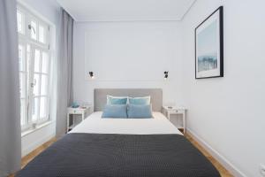 グダニスクにあるGdansk Old Town ul. Sw. Ducha 68 Apartmentsの白いベッドルーム(青い枕の大型ベッド付)