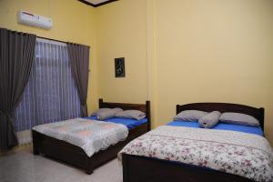 a bedroom with two beds and a window at Rumah Eyang Guest House in Banyuwangi +6 photos