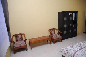 two chairs and a bench in a room at Rumah Eyang Guest House in Banyuwangi
