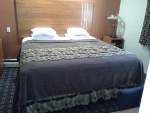 a hotel room with a bed with a blue blanket at Economy Inn Tonawanda in Tonawanda