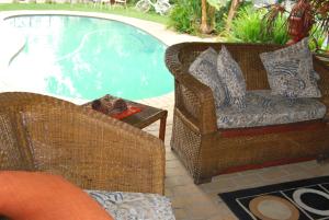 2 sillas de mimbre sentadas junto a una piscina en Ronique's Guest House, en Rustenburg