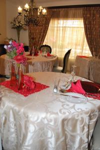 a table with a white table cloth with roses on it at Ronique's Guest House in Rustenburg
