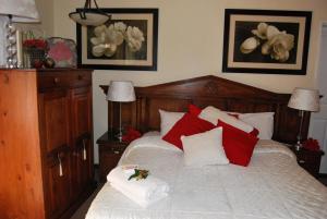 a bedroom with a bed with red and white pillows at Ronique's Guest House in Rustenburg +15 photos