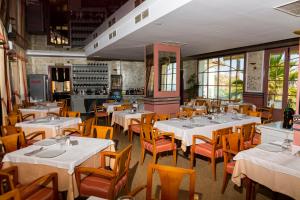 restauracja z białymi stołami i krzesłami oraz oknami w obiekcie Hotel Salambina w mieście Salobreña