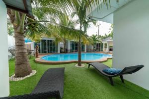 einen Garten mit einem Pool, zwei Stühlen und einer Palme in der Unterkunft Coconut Palms in Kantharawichai