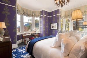 Hulbert House Luxury Boutique Lodge Queenstown في كوينزتاون: غرفة نوم بجدران أرجوانية وسرير بمخدات بيضاء