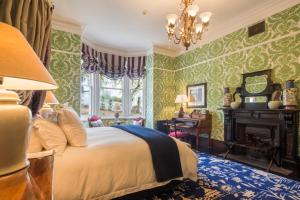 a bedroom with green wallpaper and a bed with a chandelier at Hulbert House Luxury Boutique Lodge Queenstown in Queenstown