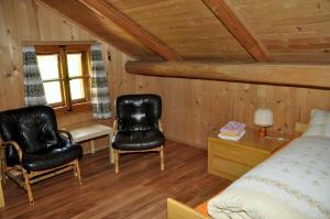 1 Schlafzimmer mit 2 Stühlen, einem Bett und einem Schreibtisch in der Unterkunft Chalet Sanpeter in Sent